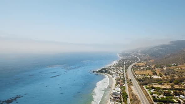 Cloudy horizon, blue ocean, coastal settlement, road and a mountain in Malibu, California, USA