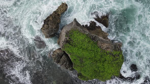 Top down aerial view of giant ocean waves crashing and foaming in coral beach