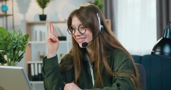 Female Freelancer in Headphones Sitting in front of Computer During Online conference