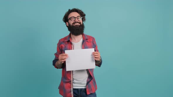 Young Bearded Man Smilling with a Clean Sheet of Paper in His Hands.