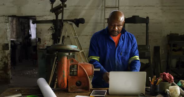 Metalsmith using laptop in workshop 4k