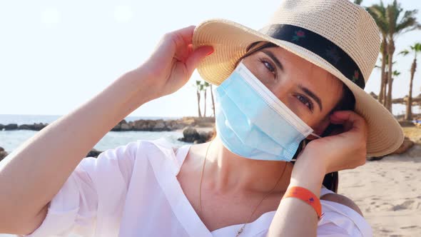 Portrait of Woman in Sun Hat, Who Takes Off Her Protective Mask, Against Sea Background, Beach