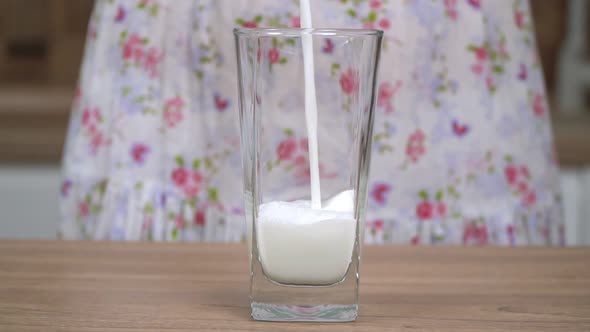 A Woman in the Kitchen Pours Milk Into a Glass Slow Motion