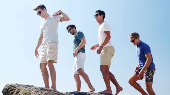 Friends walking on rock at beach