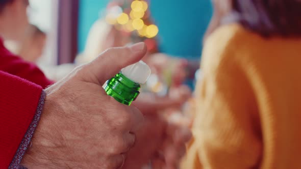 Closeup of Man Hands Opening Bottle of Champagne on Background of Christmas Family Table