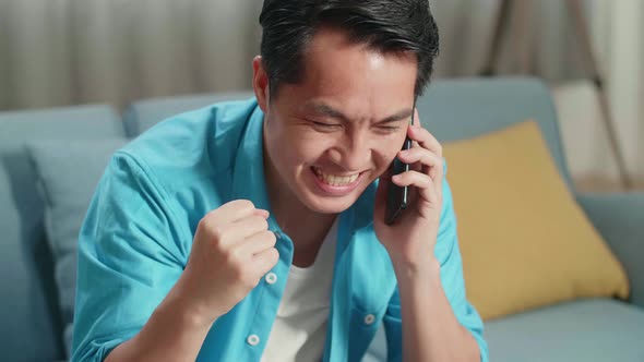 Asian Man With A Laptop Answering The Call Then Being Happy While Looking At The Bill In Hand