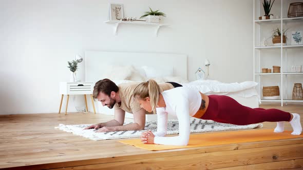 Young Couple is Doing Plank Plank Exercise at Home in Cozy Bright Bedroom