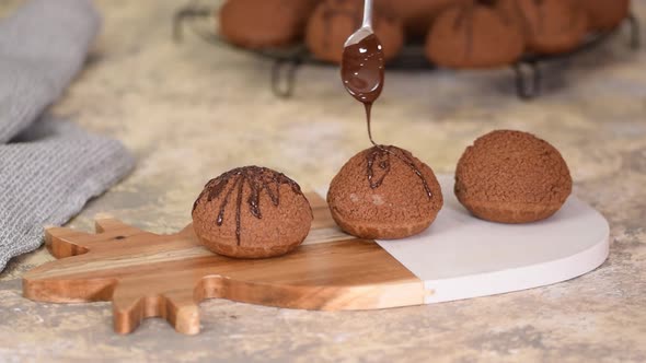 French Dessert Chocolate Choux Au Craquelin. Pouring Chocolate Over the Profiteroles.