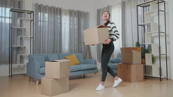 Young Asian Woman Carrying Cardboard Box With Stuff Into A New House And Looking Around