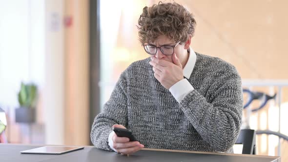 Unhappy Young Man with Loss on Smartphone at Work