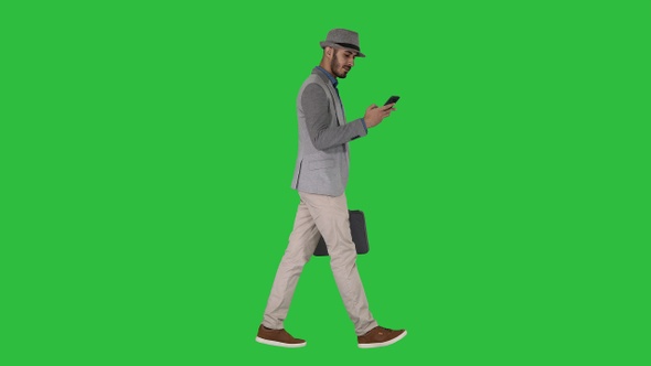 Casual man texting on phone and walking on a Green Screen