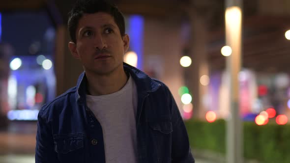 Hispanic Man Thinking While Exploring the City Streets at Night