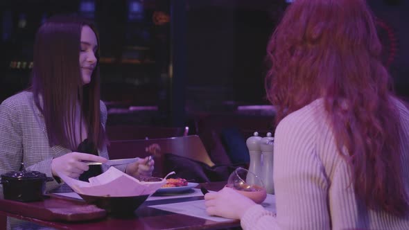 Two Pretty Girlfriends Have Dinner in a Modern Restaurant Together