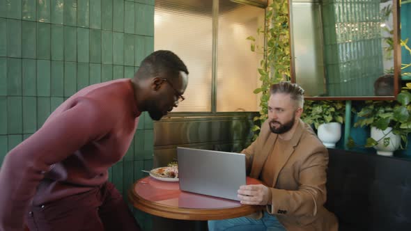 Multiethnic Businessmen Meeting in Cafe and Discussing Project on Laptop