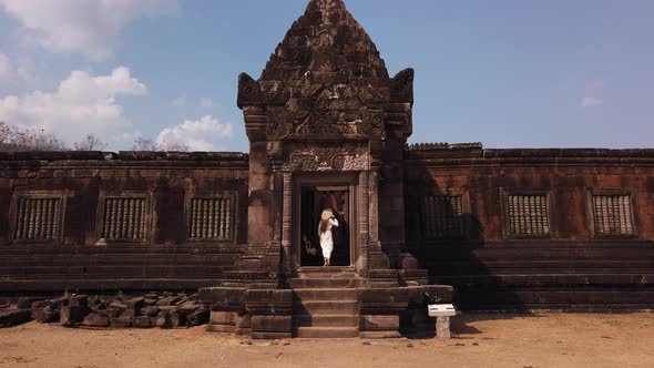 Woman in vietnamese hat go up the stairs to palace, Wat Phou Hindu Temple, ancient architecture Laos