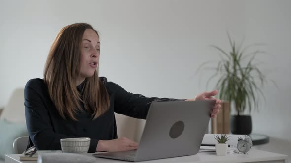 Young woman freelancer using laptop computer and  tells something to the audience