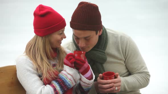 Couple drinking hot beverages at ice skating rink