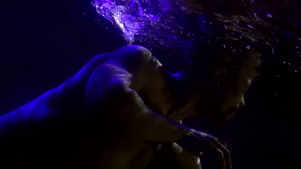 Sexy Naked Man Is Floating Underwater, Dark Swimming Pool, Subaquatic Shot