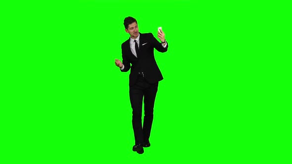 Businessman Walks, Thumbs a Notebook, and Makes a Selfie. Green Screen