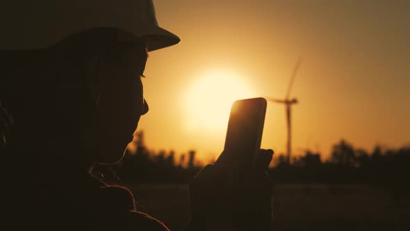 Silhouette Female Engineer Working in Wind Turbine Electricity Industrial at Sunset.