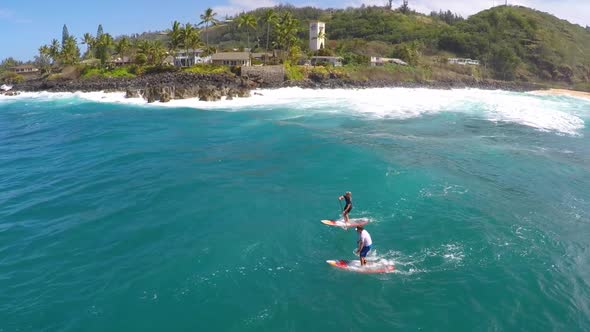 Aerial view of a man paddling while sup stand-up paddleboard surfing in Hawaii