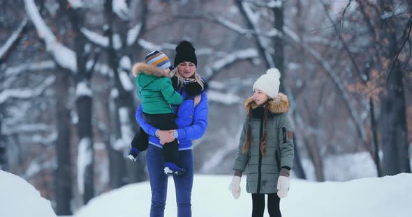 Young and Beautiful Mother Walks with Children in the Winter