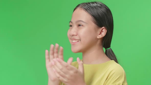 Side View Of Young Asian Kid Girl Clapping Her Hands In The Green Screen Studio