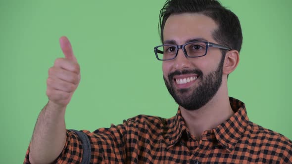 Face of Happy Young Bearded Persian Hipster Man Giving Thumbs Up