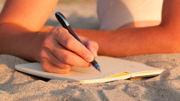 Man Writing In His Diary At The Beach