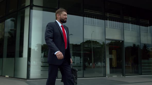 Senior Businessman in an Expensive Suit with a Briefcase in His Hand Walks Along the City Street at