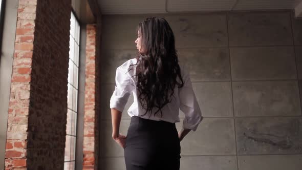 Confident Brunette Business Woman in a White Shirt Turns Around and Looks Camera