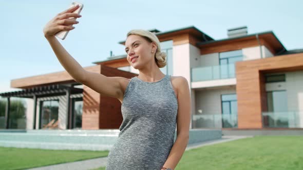 Smiling Woman Making Selfie Near Apartment. Closeup Blonde Woman Taking Photo