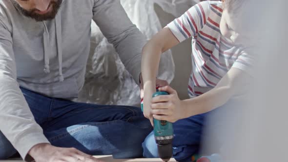 Man Teaching Boy to Use Electric Screwdriver