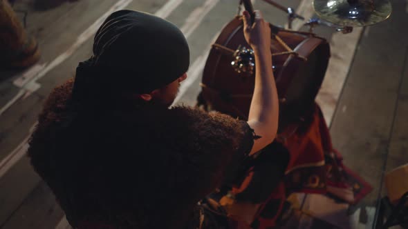 Man with Bandanna Plays Drums on Rustic Stage at Festival