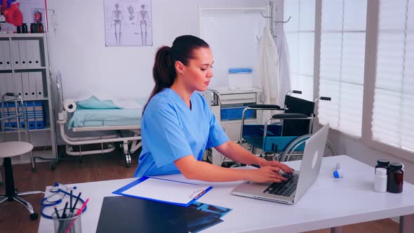 Healthcare Assistant Taking Notes on Clipboard Working in Hospital