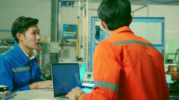 Male Asian engineer professional  having a discussion standing by the machine in the factory