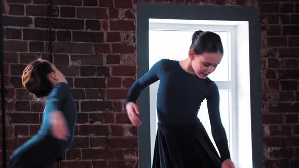 Two Smiling Ballerina Girls Dancing in Dark Costumes on Training in the Studio