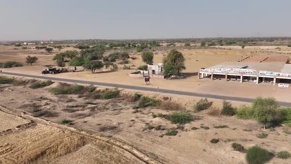 Aerial View Of Road Past Large Roadside Building In Rural Punjab. Dolly Back