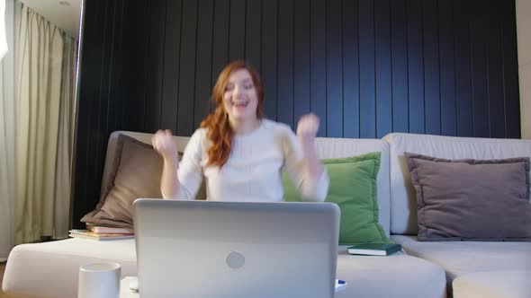 Excited Young Woman Winner Looks At laptop Celebrates Online Success Sits On Sofa At Home.