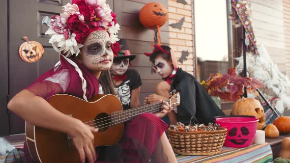 Girl in Halloween Costume Playing Guitar