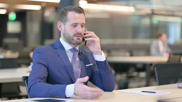 Middle Aged Businessman Talking on Smartphone at Work