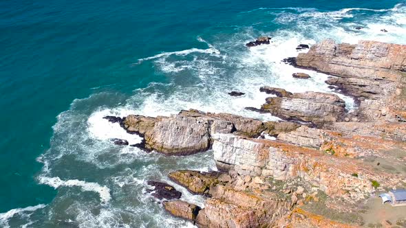 Aerial drone view of a beautiful tourist destination with rocky coastline and waves crashing into it