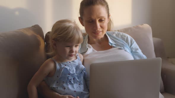 Mother and Daughter in Casual Clothes on Sofa Using Laptop