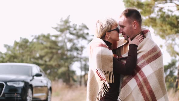 Portrait of Couple Covered with Blanket Embracing in Forest