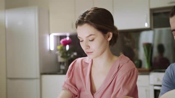 A Young Woman is Typing Something on the Laptop While Her Husband is Reading a Book