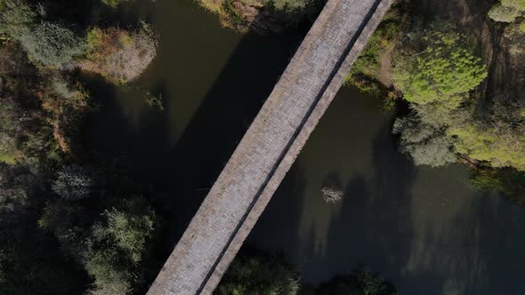 Ancient roman stone bridge over Seda river, Vila Formosa in Portugal. Aerial top-down orbit rising