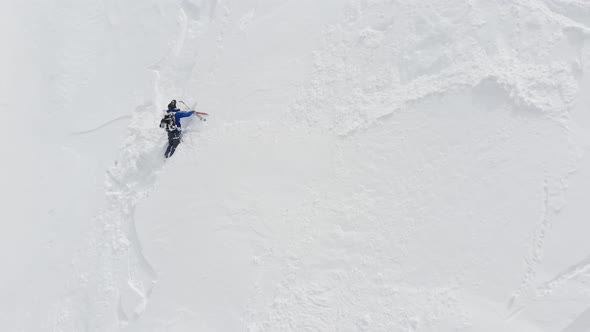 An Aerial View of a Male Athlete Athlete Skier Clambering Up a Steep Slope Up. Skitour Freeride