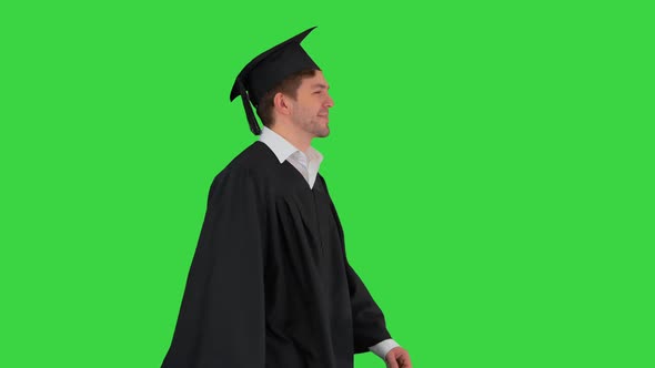 Smiling Male Student in Graduation Robe Walking with His Diploma on a Green Screen, Chroma Key.