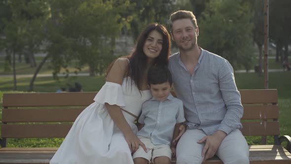 Happy Interracial Family Sitting Bench Sunny Park Smiling Camera