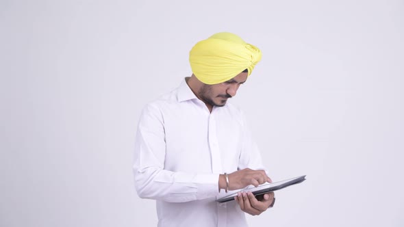 Happy Bearded Indian Sikh Businessman Using Digital Tablet and Getting Good News